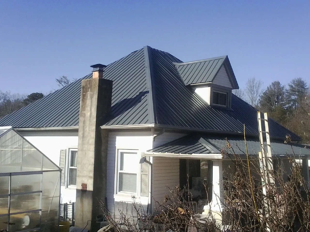 Dark blue standing seam metal roof on a white farmhouse with dormer — Slate & Tile Roof Repair by Roofing Brothers in Ingleside