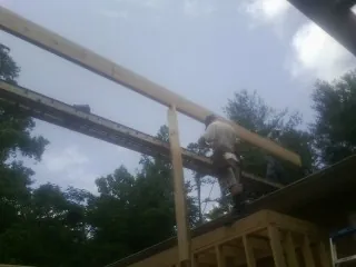 Carpenter setting a ridge beam over a new addition frame — Ice Dam Removal by Roofing Brothers in Ingleside