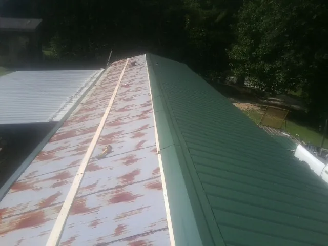 Old rusted panels beside newly installed green metal roofing — Wind Damage Roof Repair by Roofing Brothers in Ingleside