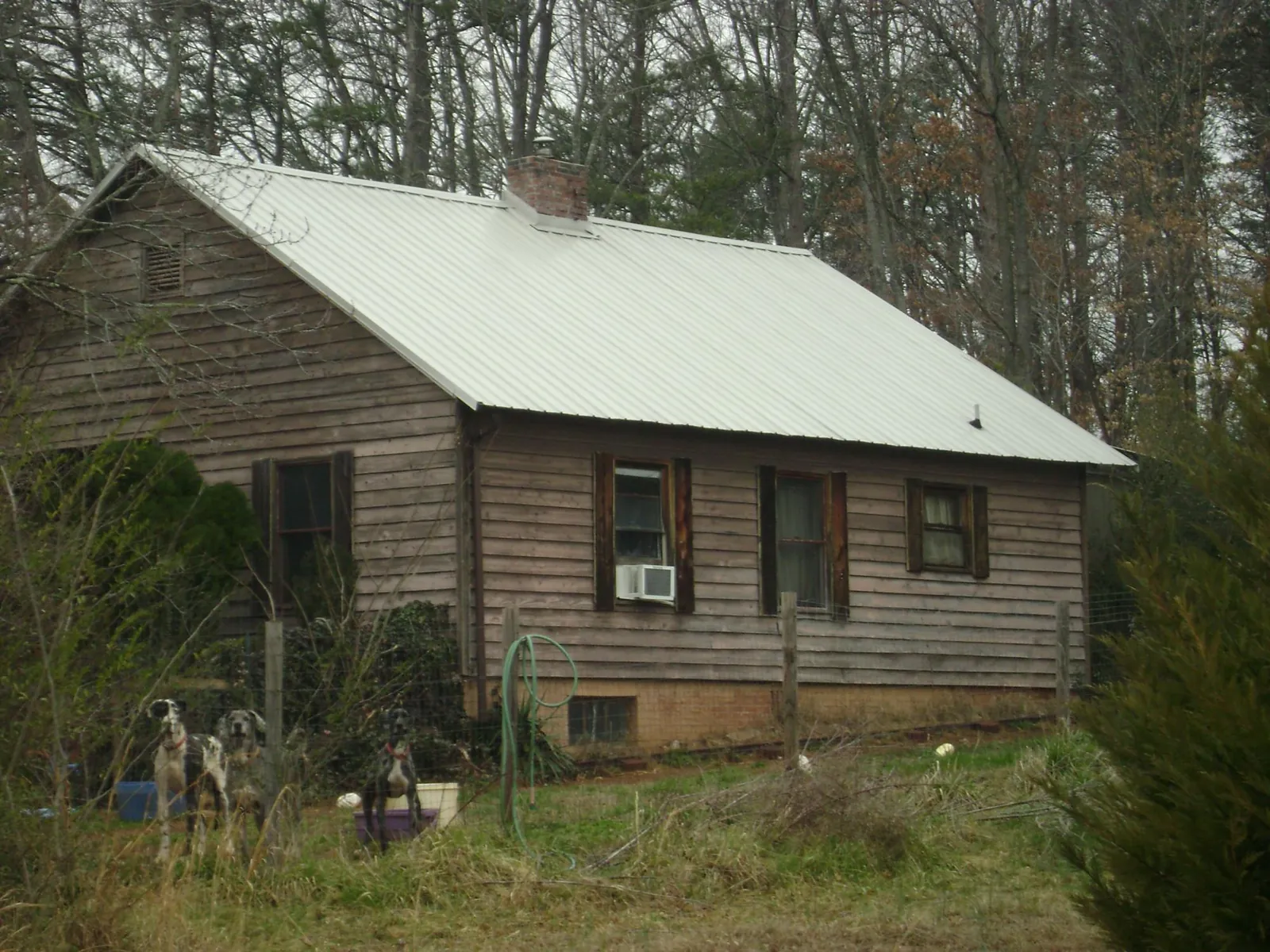 White metal roof on an old wood sided farmhouse, from a Metal Roof Installation job in Ingleside